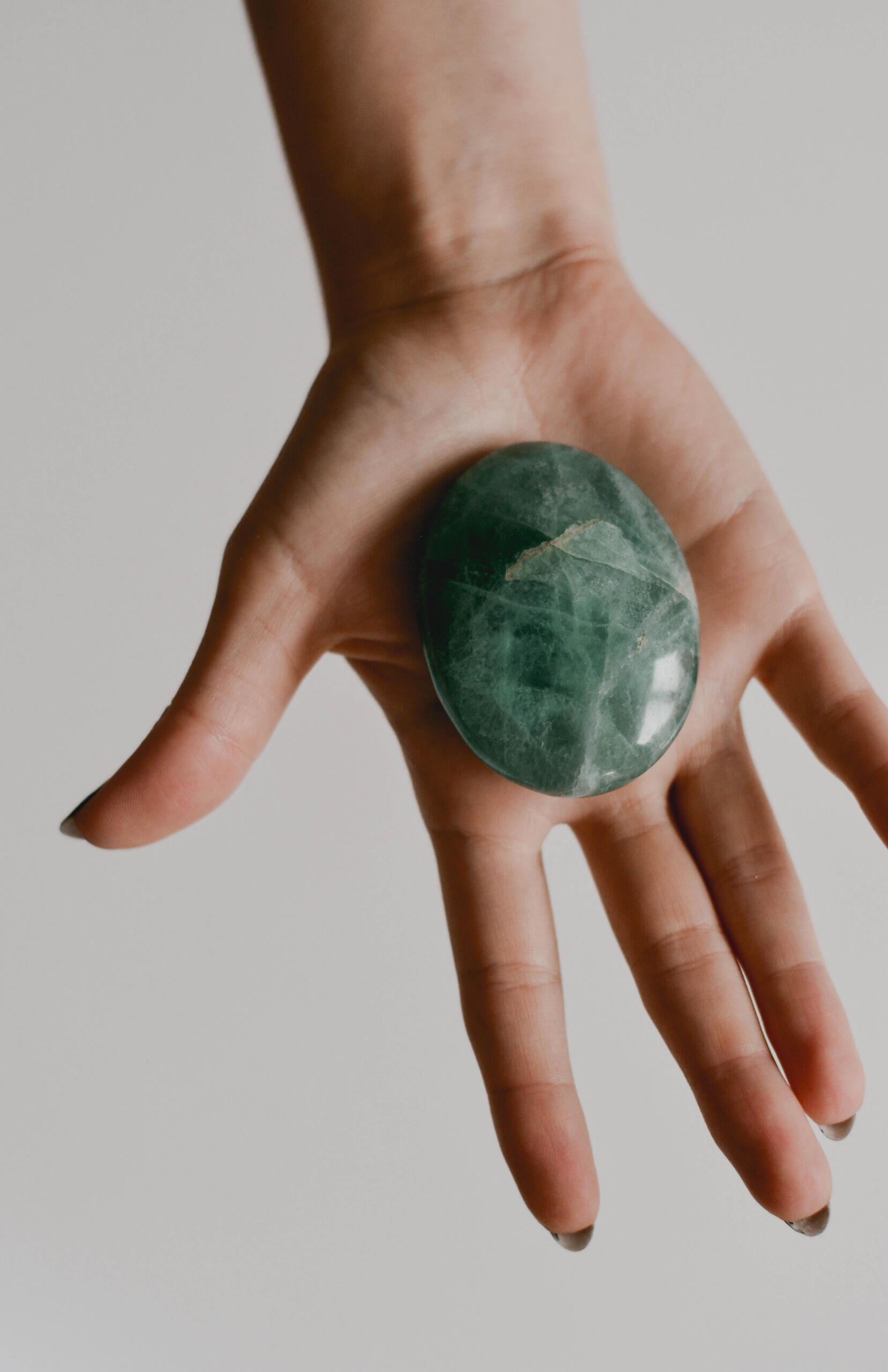 Image of a hand holding a Green Fluorite palmstone crystal